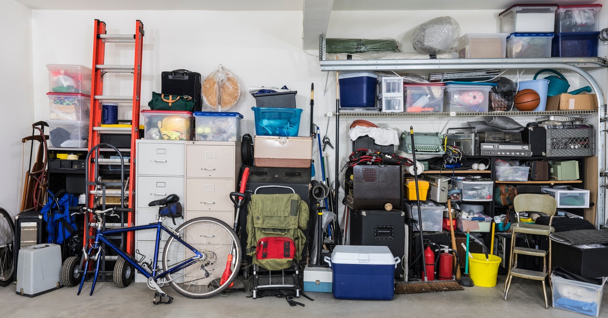 A garage wall with storage shelves, cabinets, and bins. The space also has a ladder, a bike, and household items.