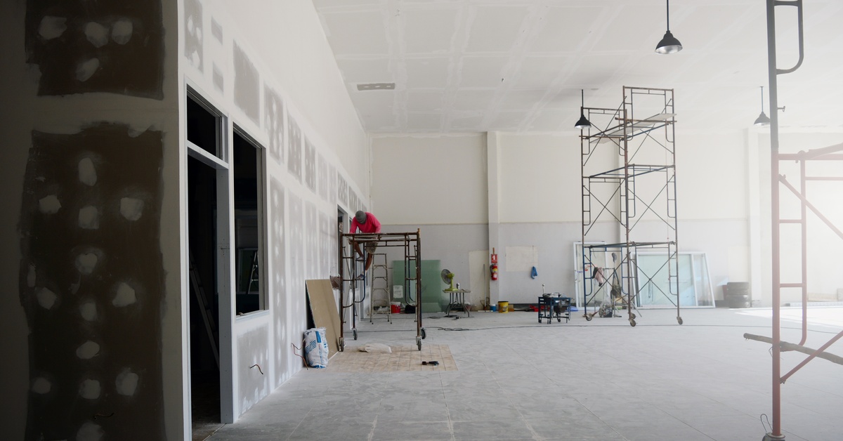 A large room that is unfinished. There is scaffolding and various pieces of equipment scattered throughout the room.